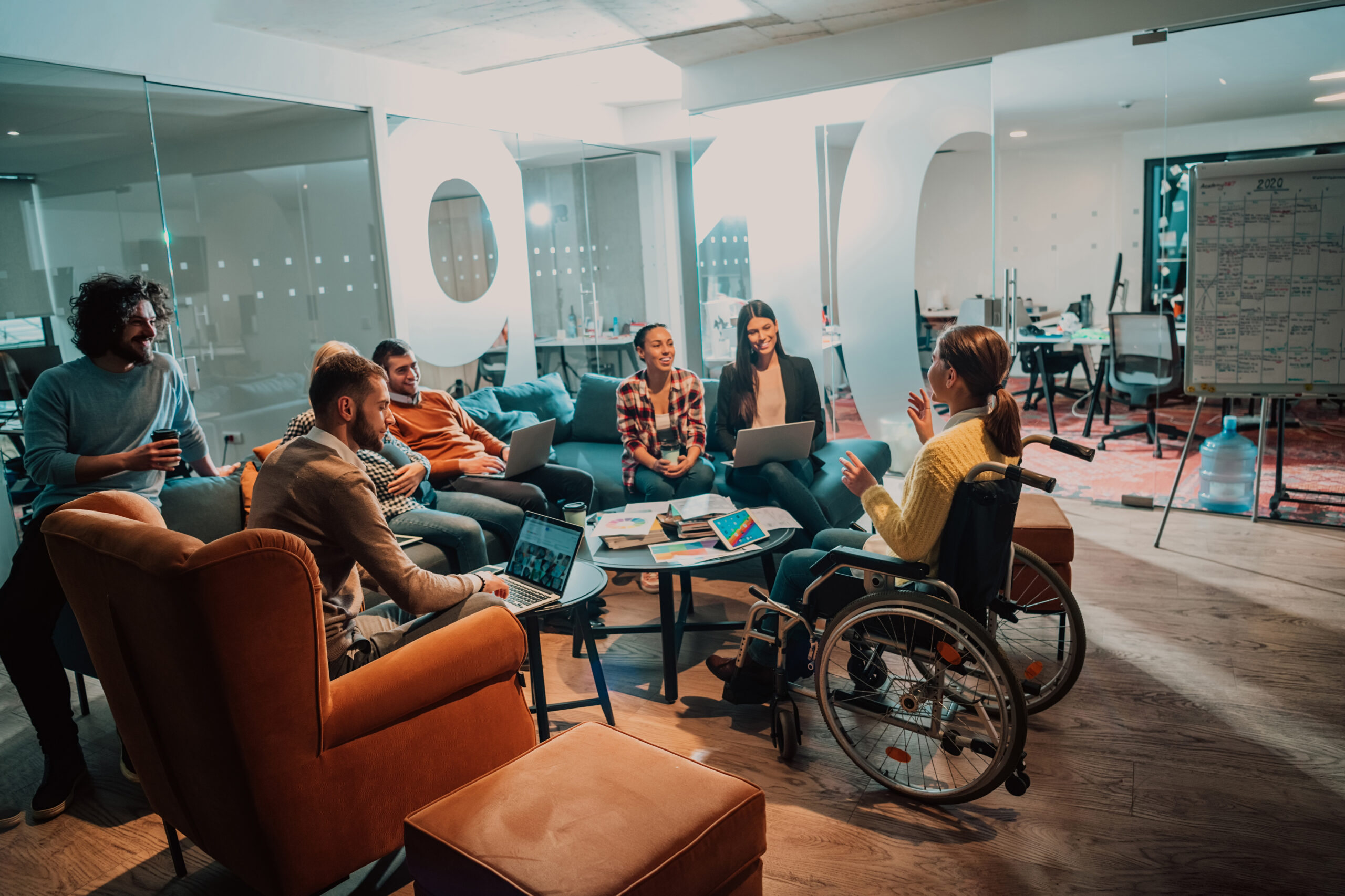 A businesswoman in a wheelchair having a business meeting with the team at a modern office. A group of young freelancers agree on new online business projects.